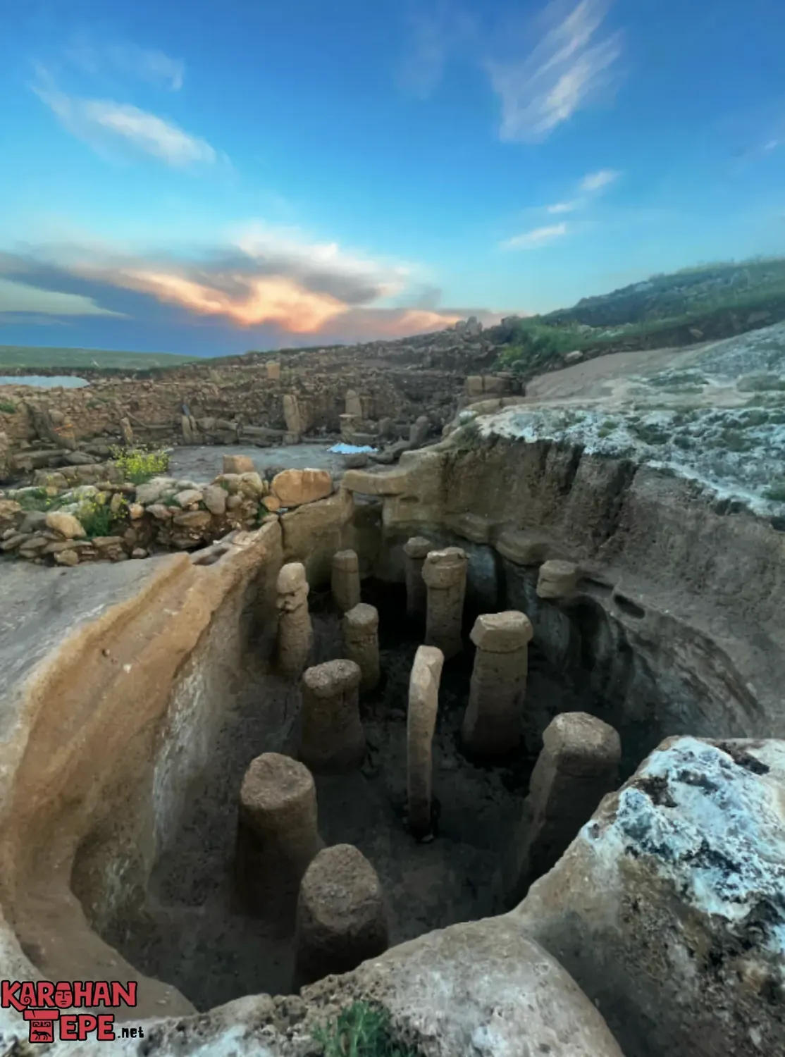A sunken rock-cut chamber of pillars at Karahan Tepe seen from above at dusk