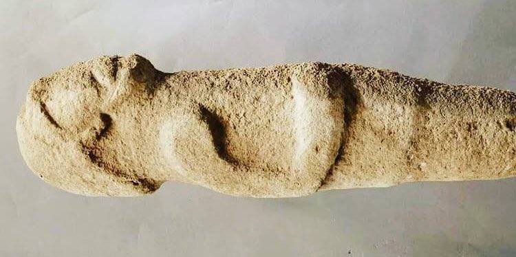 A closer view of the carved human figure, its head and torso clearly defined.
