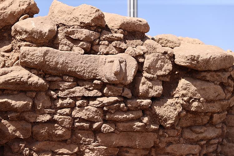 Human heads carved into the walls of the roughly 17-metre circular building, with the curved stone benching below.