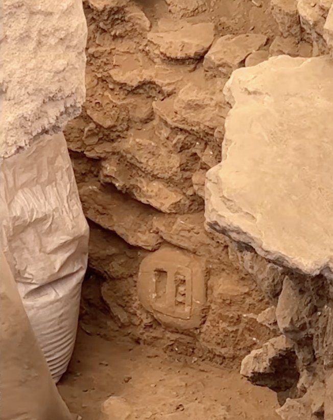 A miniature porthole stone recorded in situ at Sayburç — a small pierced slab echoing the big threshold stones of the monumental buildings.